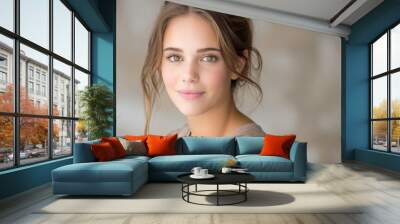 Portrait of a young woman with natural makeup and soft lighting, looking into the camera with a gentle expression. Wall mural