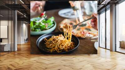 Family or friends eating food together. people eating Italian food Pasta, Pizza, Salad on the table. Wall mural