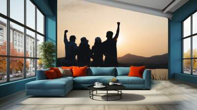 group of people with raised arms looking at sunrise on the mountain background. Happiness, success, friendship and community concepts. Wall mural