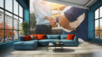 Man holding hard hat are shake hand on site construction concept teamwork business worker Wall mural