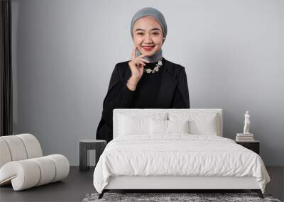 Portrait of an Asian business woman on a white background wearing a black suit. Wall mural