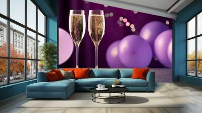 two champagne flutes filled with champagne are on a table with purple balloons Wall mural