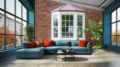 Bay window with copper roof on traditional brick home with flowers below and yellow roses extending out onto the window in springtime Wall mural