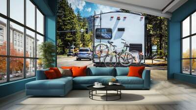 Camper with two bicycles tied to back on tree-lined highway outside of Lake Tahoe with mountains in distance on sunny summer da Wall mural