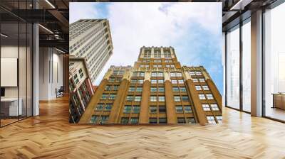 Perspecitive view of new and old office buildings looking up at them from ground level against cloudy blue sky - room for copy Wall mural