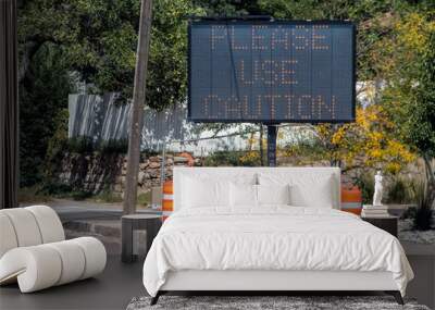 Solar mobile sign with orange cones sitting on sidewalk besides road saying Please Use Caution - Selective focus Wall mural