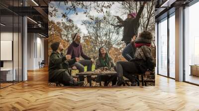 Woman with friends throwing up leaves in the park Wall mural