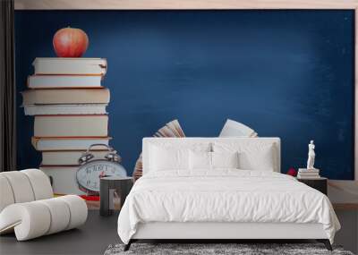 open book with magnifying glass, golden ball, alarm clock, colored pencils, stack of books, red apple and blue chalkboard on the wood table with copy space	 Wall mural