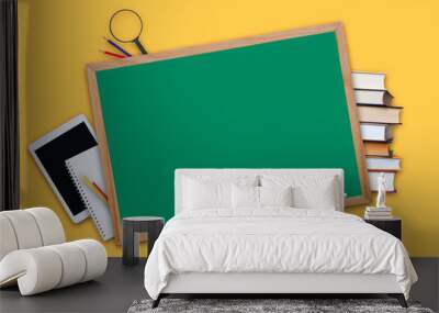 stack of books and open book with red apple, magnifying glass, tablet, notebook, pencils, maple leaves and blackboard Wall mural