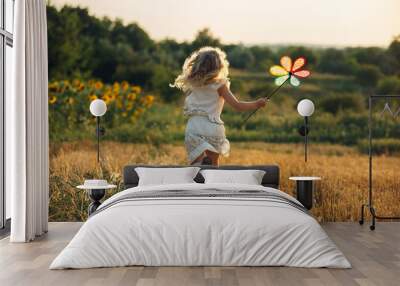 Cute little girl playing in the summer field of wheat Wall mural