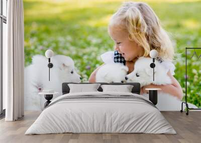 happy little girl playing with Samoyed puppy Wall mural