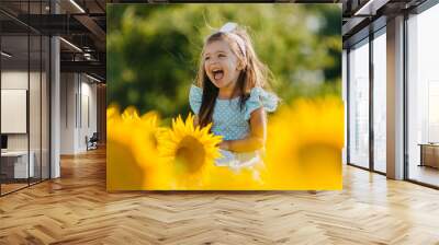 Little cheerful girl in a field of yellow sunflowers. Child and sunflower, summer, nature and fun. Summer rest Wall mural