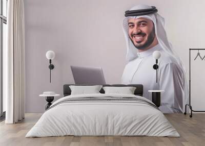 Arab Abaya businessman smiling, holding a laptop, working on a white background. Wall mural