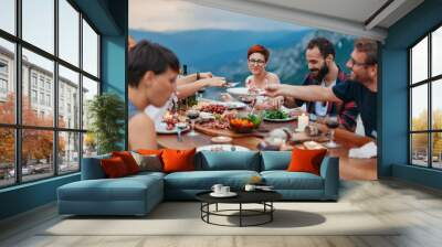 Friends and family gathered for picnic dinner for Thanksgiving. Festive young people celebrating life with red wine, grapes, cheese platter, and a selection of cold meats Wall mural