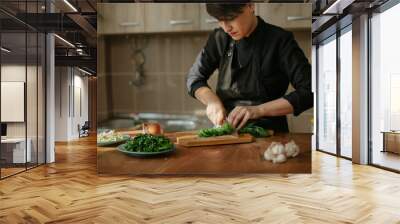 Portrait of female chef preparing a recipe in the kitchen with vegetables. Woman cook chopping spinach leaves for vegetarian dish. Wall mural