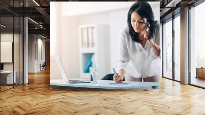 Woman taking notes at the office while on the phone Wall mural