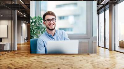 Young businessman in office working on laptop Wall mural