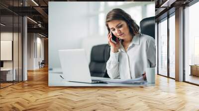 Young woman in office talking on a cell phone Wall mural