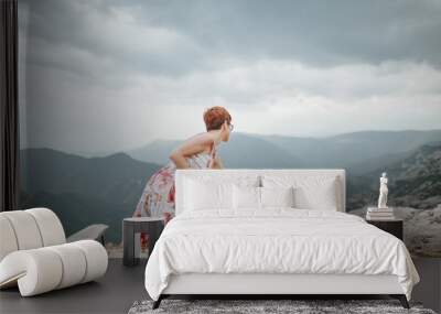 Young woman setting up table for picnic outdoors. Mountain top view and canyon in background Wall mural