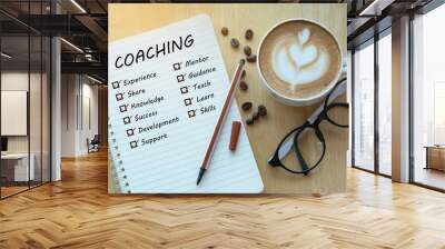 coaching and check list marks in notebook with glasses, pencil and coffee cup on wooden table. Project management concept. Wall mural