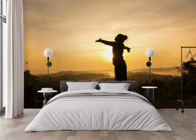 silhouette of free cheering woman open arms at mountain peak sunrise Wall mural