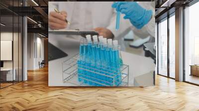 Health care researchers working in life science laboratory. Young female research scientist and senior male supervisor preparing and analyzing microscope slides in research lab. Wall mural