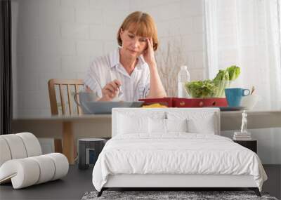 Elderly retired grandmother stay at home with painful face sitting alone on eating table in house. Depressed mature senior old woman upset feeling unhappy. Lonely and missing his family at home Wall mural