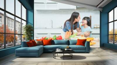 Family. Children and happy people concept. Asian mother and kid daughter cooking in the kitchen at home Wall mural