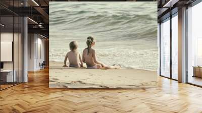 Little boy and girl sitting on the sand, sitting together in the sand looking at the sea, Blurred background, Film simulation Wall mural