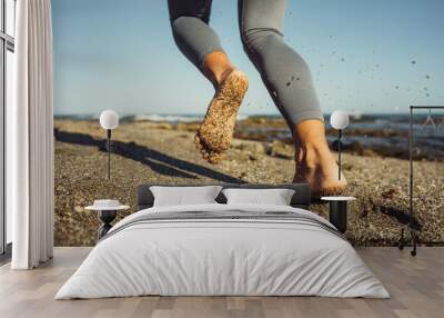 close-up of female feet barefoot running on the sand against the backdrop of the sea Wall mural