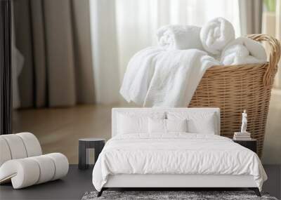 A laundry basket with white towels, freshly laundered and folded, placed on a wooden floor in a modern home. Wall mural