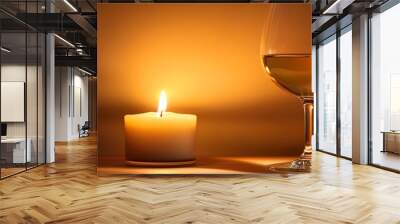 Cozy scene with a glowing candle and a glass of wine, creating a warm and relaxing ambiance perfect for unwinding and enjoying a quiet evening. Wall mural