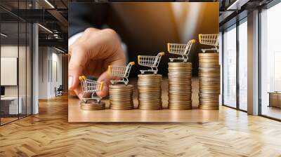 A professional hand carefully places a mini shopping cart on a coin stack, symbolizing investment, growth, and financial success in business. Wall mural