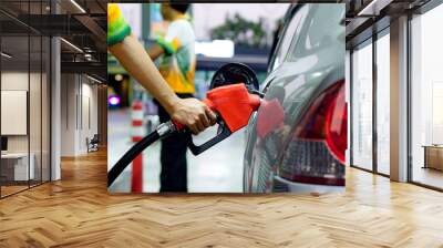 A man uses his hand to open a gasoline or diesel nozzle. To fill a car parked at a gas station with a gasoline or diesel dispenser. Wall mural