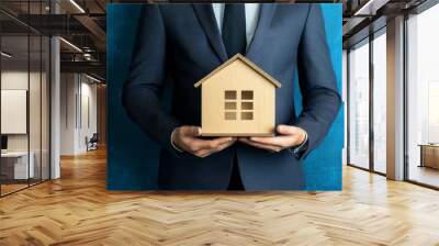 Businessman holding a small house model in hand, symbolizing savings, investment in real estate, showcasing the importance of financial planning, home ownership in today's economy for potential buyers Wall mural