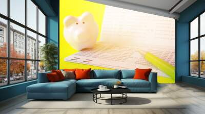 Business, finance, investment or savings money concept : Savings account passbook, piggy bank and pen on yellow background Wall mural