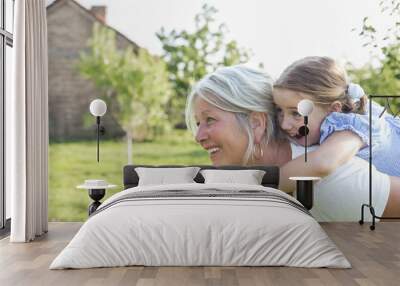 Little girl on a piggy back ride with her grandmother Wall mural