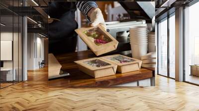 Restaurant worker wearing protective mask and gloves packing food boxed take away. Food delivery services and Online contactless food shopping. Wall mural