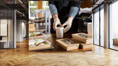 Restaurant worker wearing protective mask and gloves packing food boxed take away. Food delivery services and Online contactless food shopping. Wall mural