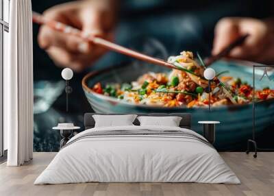 A close-up shot of a person using chopsticks to eat a steaming bowl of mixed vegetables and noodles, highlighting the vibrant colors and textures of the ingredients. Wall mural