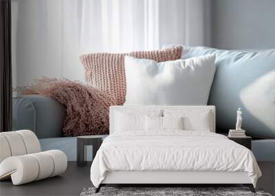 A comfortable light blue sofa adorned with pink and white cushions, along with a textured pink throw, creating a soft and inviting space for relaxation and repose in a well-lit room. Wall mural