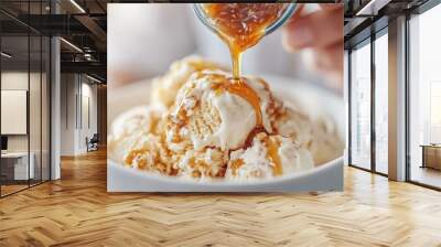 A delectable bowl of ice cream featuring scoops of vanilla topped with a caramel drizzle swirl, creating a visually appealing and appetizing dessert, perfect for food photography. Wall mural