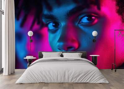 An abstract image featuring a blurred face with a vibrant combination of pink and blue lighting, creating an atmospheric and mysterious feel. Wall mural