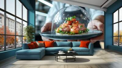 Chef's hands elegantly present a colorful, fresh dish with fruits and vegetables under a glass cover, emphasizing healthy and visually appealing culinary creation. Wall mural