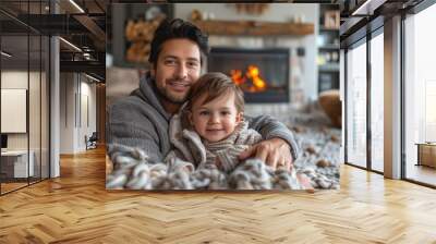 Happy father and young son cuddling together on a blanket in front of a warm fireplace Wall mural