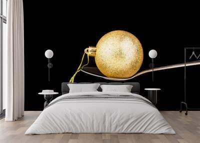 Golden shiny ball Christmas toy on a spoon isolated on black background Wall mural