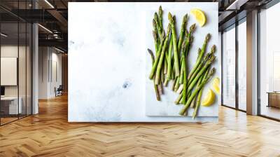 Bunch of fresh green asparagus on marble board. Green asparagus seasonal spring cooking. Overhead view, white background Wall mural