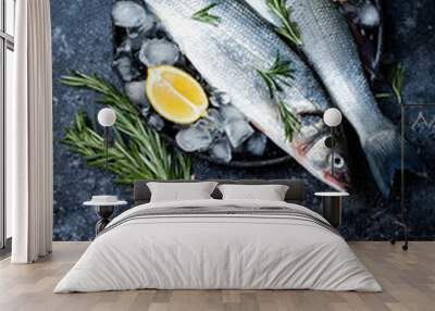 Fresh raw seabass fish on black stone background with spices, herbs, lemon and salt. Culinary seafood background with ingredients for cooking. Top view Wall mural