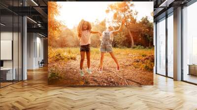 Two happy girls as friends hug each other in cheerful way. Little girlfriends in park. Wall mural