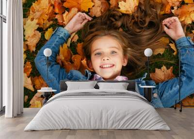 Autumn portrait of happy smiling little girl child lying in leaves in the park Wall mural